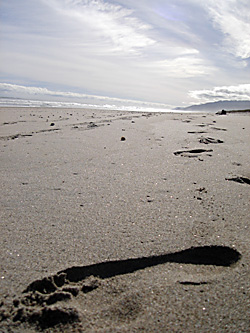 Fußspur im Sand unter weitem Himmel